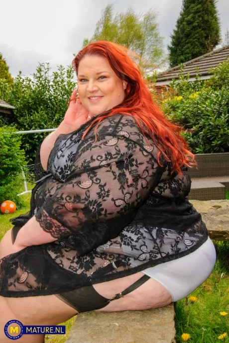 Патологически тучная рыжеволосая пожилая женщина с фаллоимитатором в поясе с подвязками и нейлонов