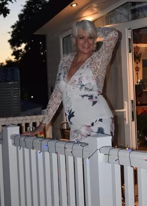 Одетая девушка Саша садится на корточки, чтобы пописать за бетонным блоком на дорожке