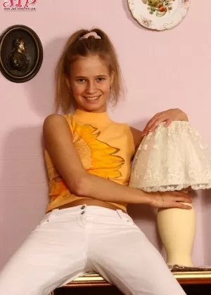 Молодо выглядящая девушка выставляет напоказ свою тугую попку и гладкую щелку в белых чулках