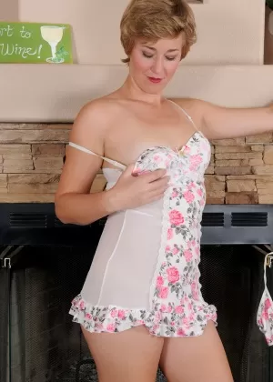 Дама средних лет с короткими волосами снимает нижнее белье, чтобы позировать обнаженной у камина