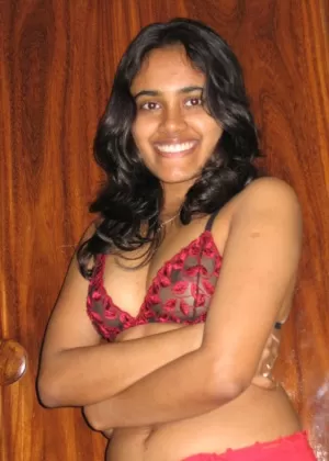 Indian girl with a nice smile shows her breasts on top of a bed