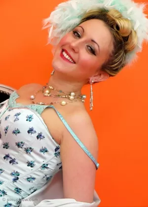 Брюнетка в пинапе выставляет напоказ задорные сиськи в винтажном кружевном корсете на высоких каблуках