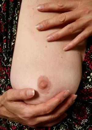 Пожилая женщина обхватывает грудь руками, прежде чем продемонстрировать свой волосатый куст на диване