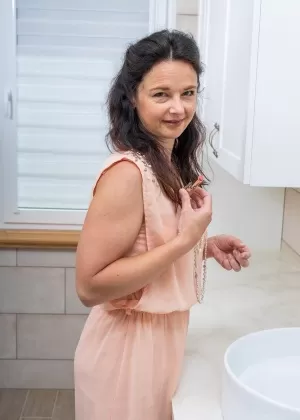 Зрелая женщина Анетт Харпер наносит блеск для губ перед тем, как дебютировать обнаженной