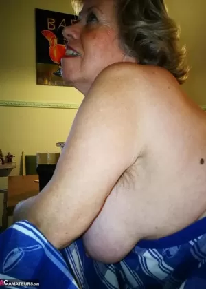 Толстая пожилая женщина Сара сбрасывает нижнее белье, чтобы позировать в чулках на столешнице