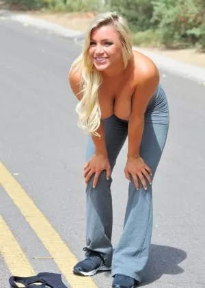 Стройная блондинка сногсшибательница снимает свою спортивную одежду на улице