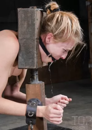 Женщина с кляпом во рту борется с цепями, будучи связанной в обнаженном виде