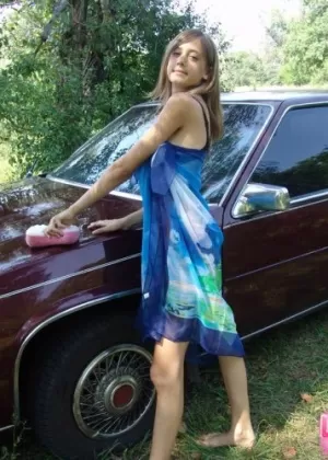 Любительская девушка надевает накидку поверх бикини, когда начинает мыть машину