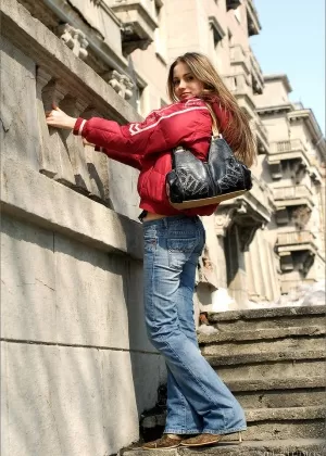 Стройная сексуальная блондинка в обтягивающих джинсах и рубашке на животе позирует одетая на открытом воздухе