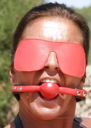 Татуированная женщина с красными губами надела повязку на глаза, будучи связанной