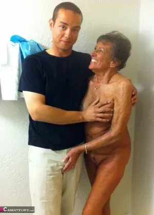 Возбужденная бабушка с седыми волосами раздевается игрушечным мальчиком до коричневых чулочно-носочных изделий