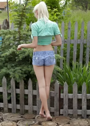 Милая блондинка из России раздевается, чтобы позировать обнаженной в саду