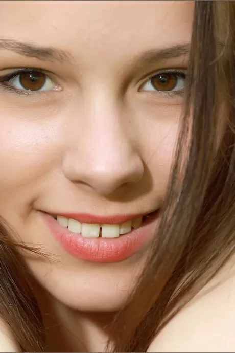 Очаровательная молодая девушка с симпатичным личиком позирует голышом возле деревьев