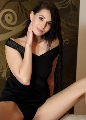 Solo girl with long black hair removes a little black dress to model naked