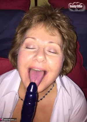 Mature woman Busty Bliss licks a penis while playing with a sex toy