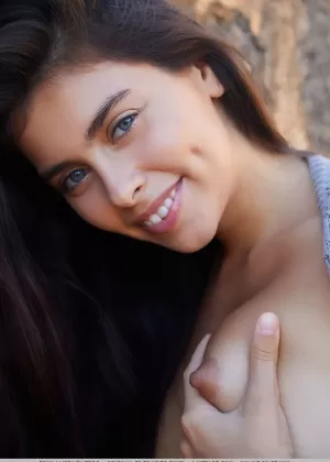 Симпатичная молодая девушка Пенни стоит голая у кирпичной стены в одиночестве