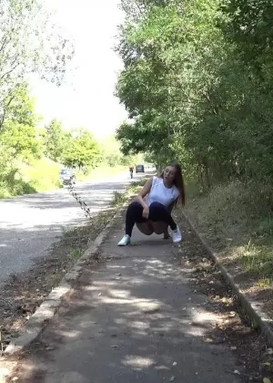 Огорченная женщина Лукка стягивает черные леггинсы, чтобы помочиться на тротуар