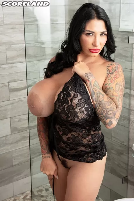 Татуированная мамаша Ricki Raxxx обнажает свои большие фальшивые сиськи во время раздевания