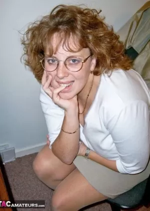 Зрелая рыжеволосая пышногрудая блондинка надевает сапоги до бедер после раздевания до нижнего белья